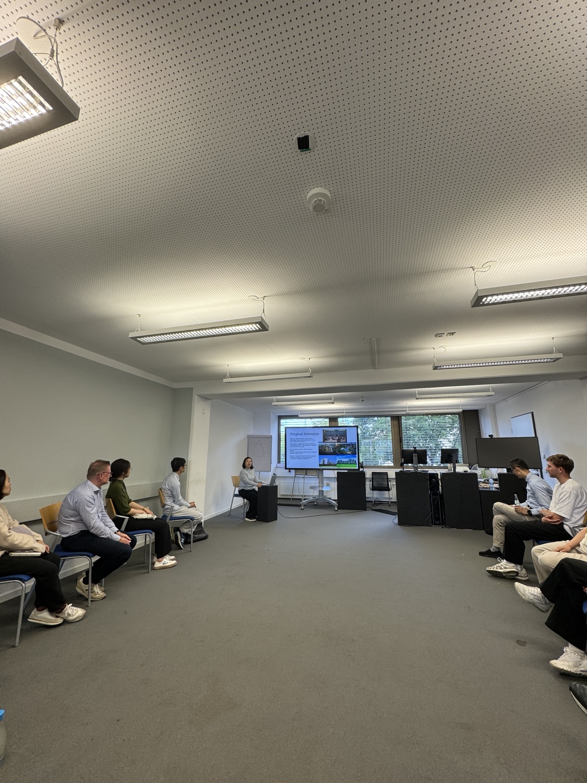 The MDH team seated in an open circle facing a presentation slide during a collaborative session on campus.
