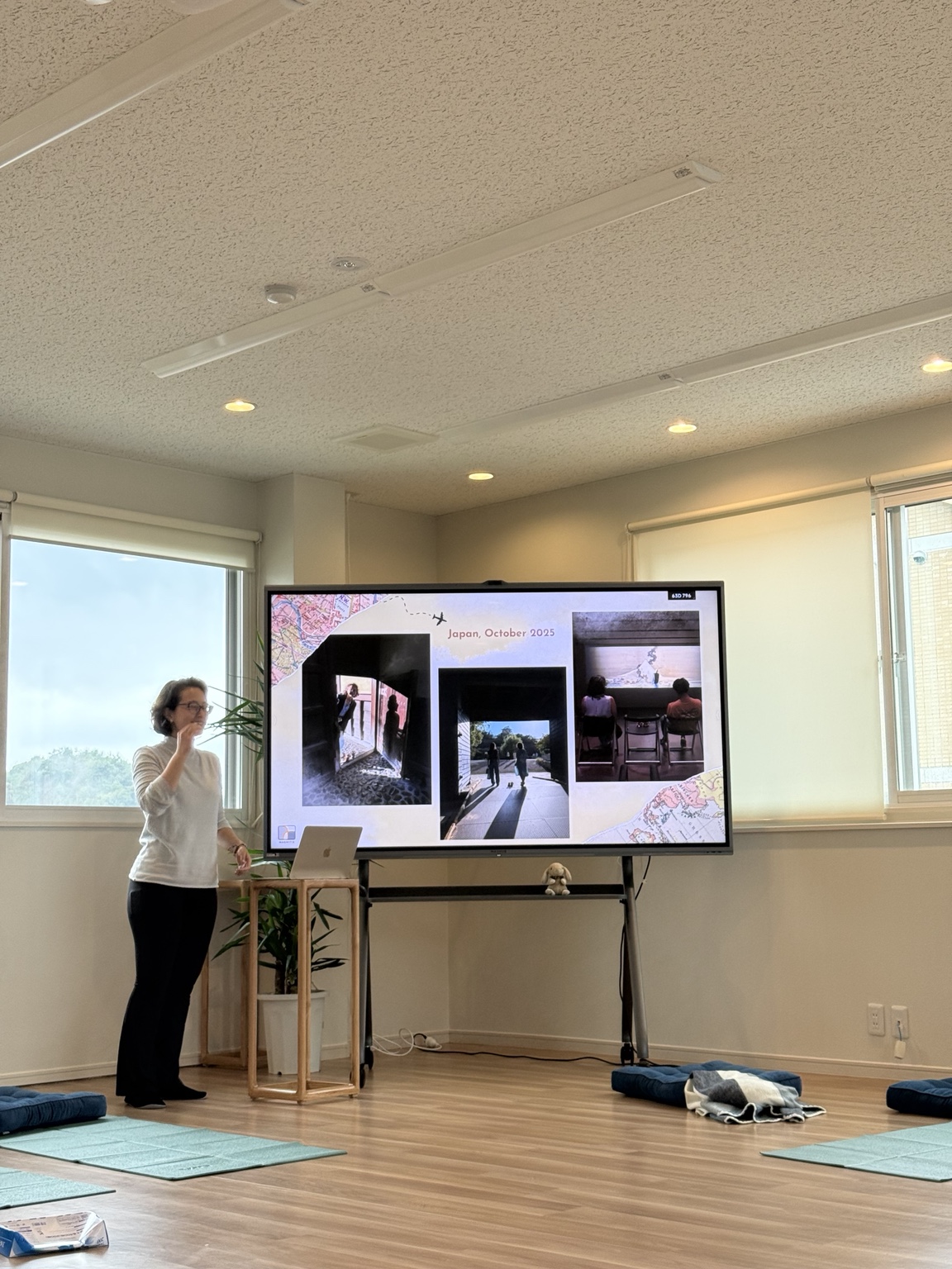 A speaker presenting a slide about Japan to the group during a knowledge-sharing session in the studio.