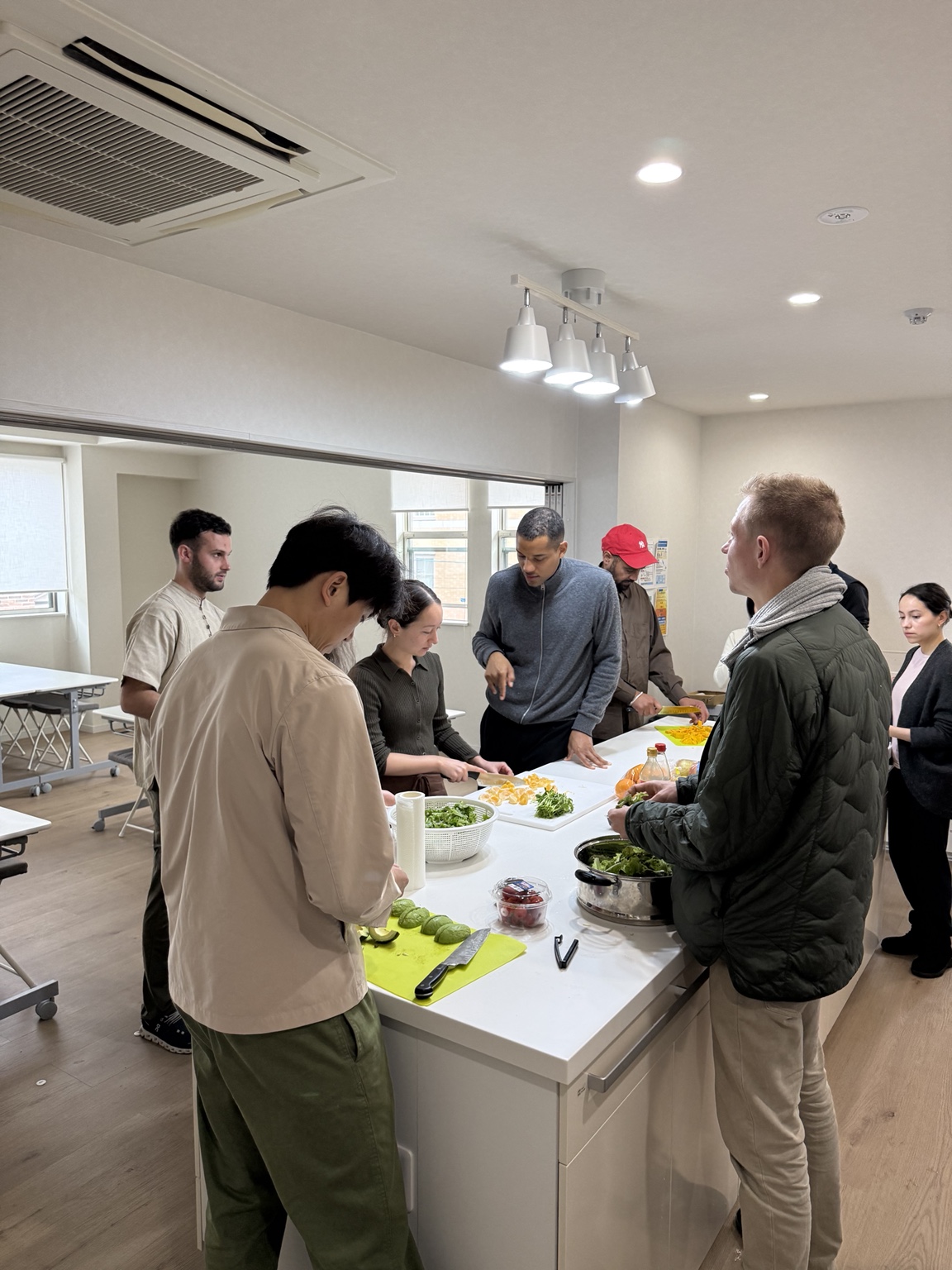 Participants gathered around a white kitchen island chopping vegetables and citrus during the plant-based cooking workshop.